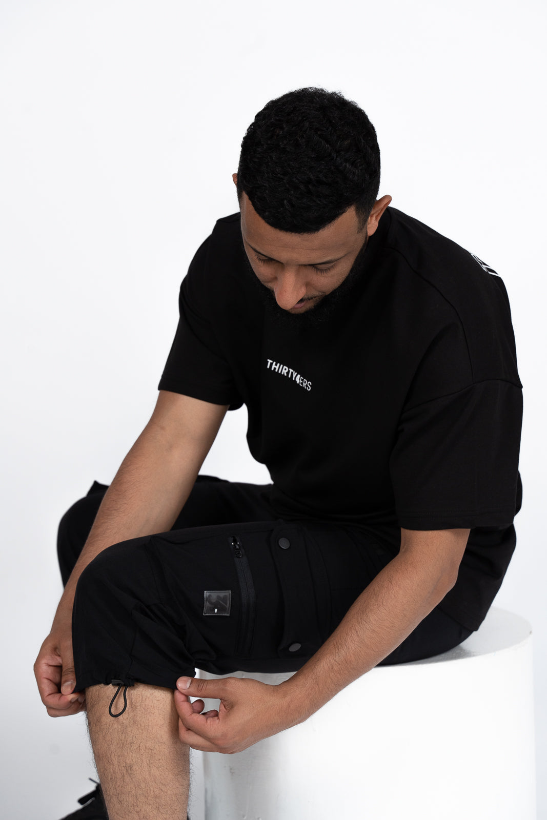 Man adjusting bungee cord on premium black 3/4 modest prayer shorts