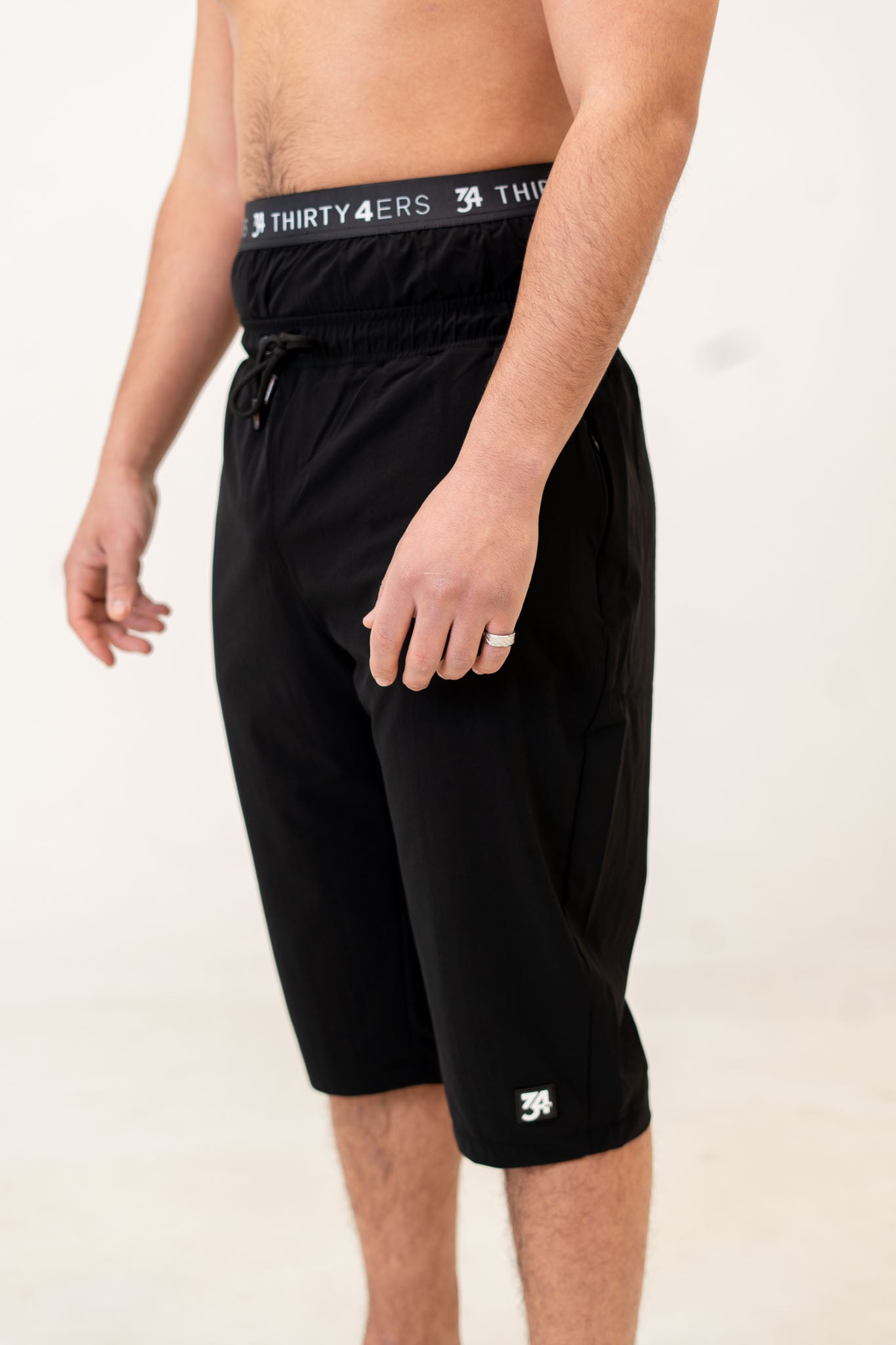 Angled view of men's modest swim shorts in all-black design with branding

